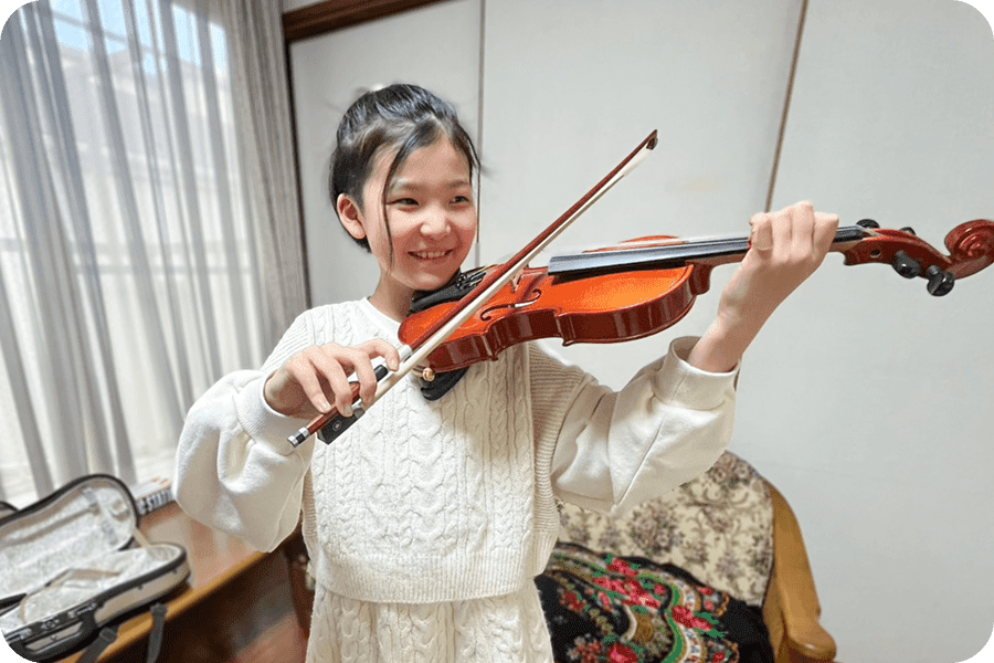 バイオリンを笑顔で弾く女の子の写真